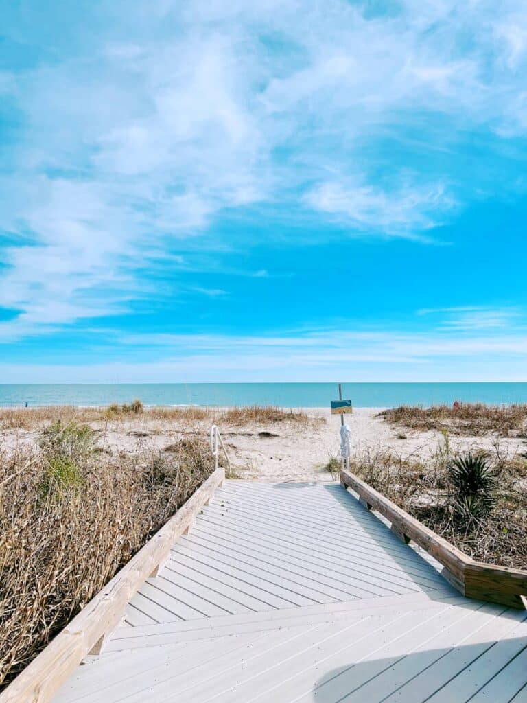 Explore the tranquil view of Myrtle Beach's sandy shore via this wooden walkway on a clear summer day.