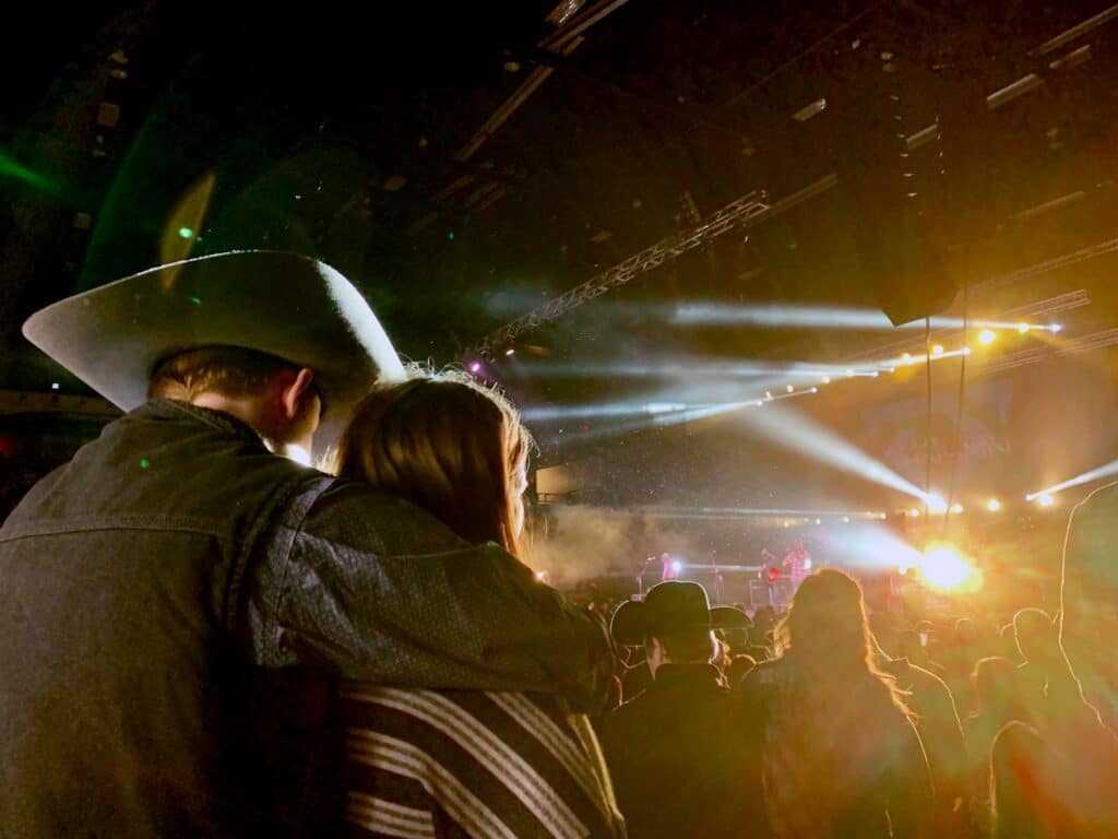 Couple enjoying a vibrant live country concert under bright stage lights.