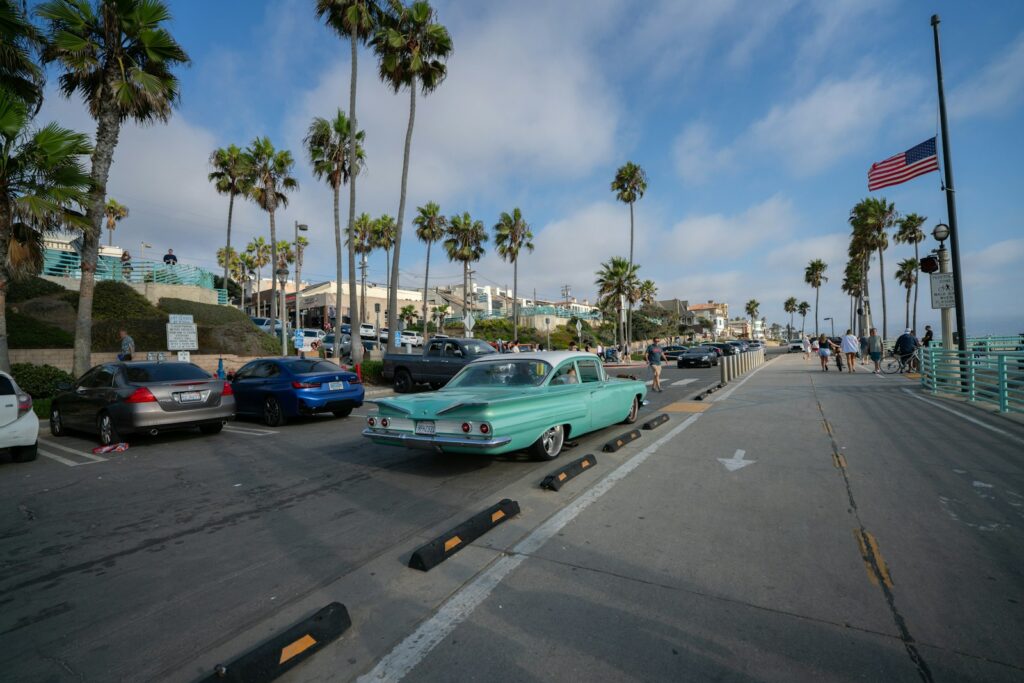 Vintage car parked near palm trees by the ocean.