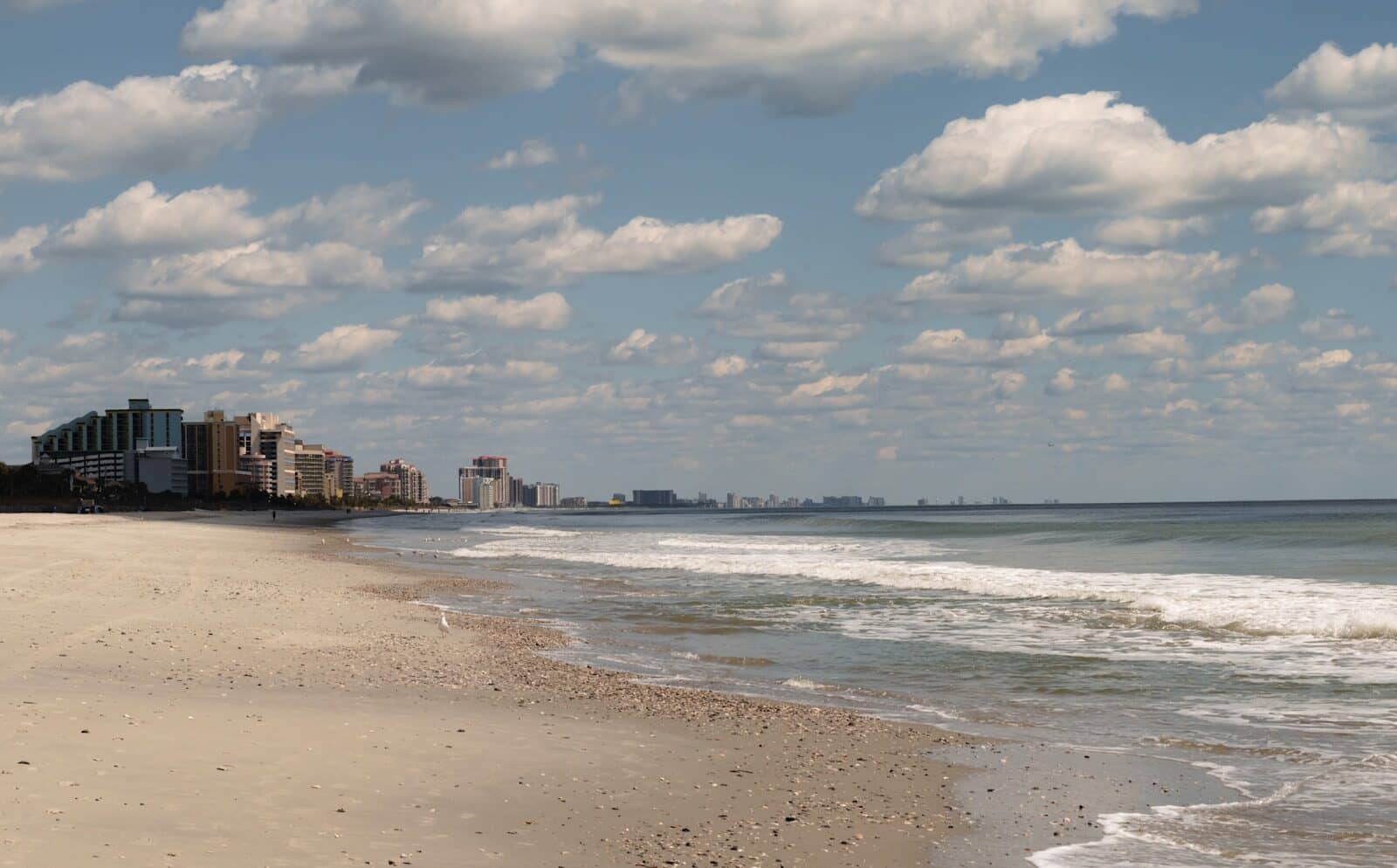 a sandy beach next to the ocean under a cloudy blue sky The Ultimate Guide to the Best South Carolina Beaches for Your Getaway
