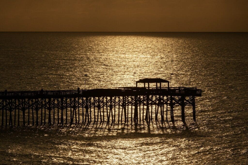 Pier silhouetted against the golden ocean.