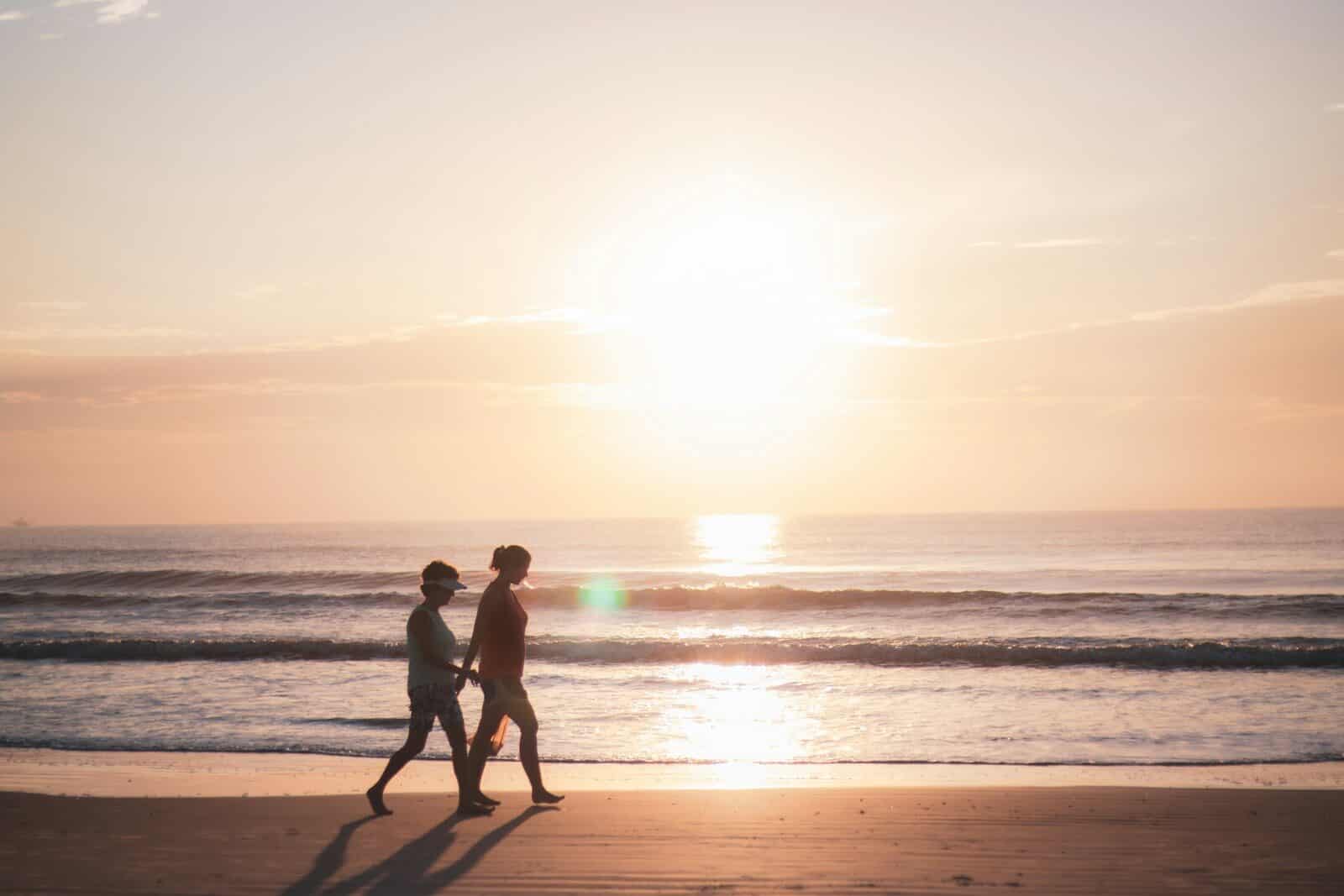 2 men standing on beach during sunset Unveil the Most Incredible Sunrise Myrtle Beach Has To Offer