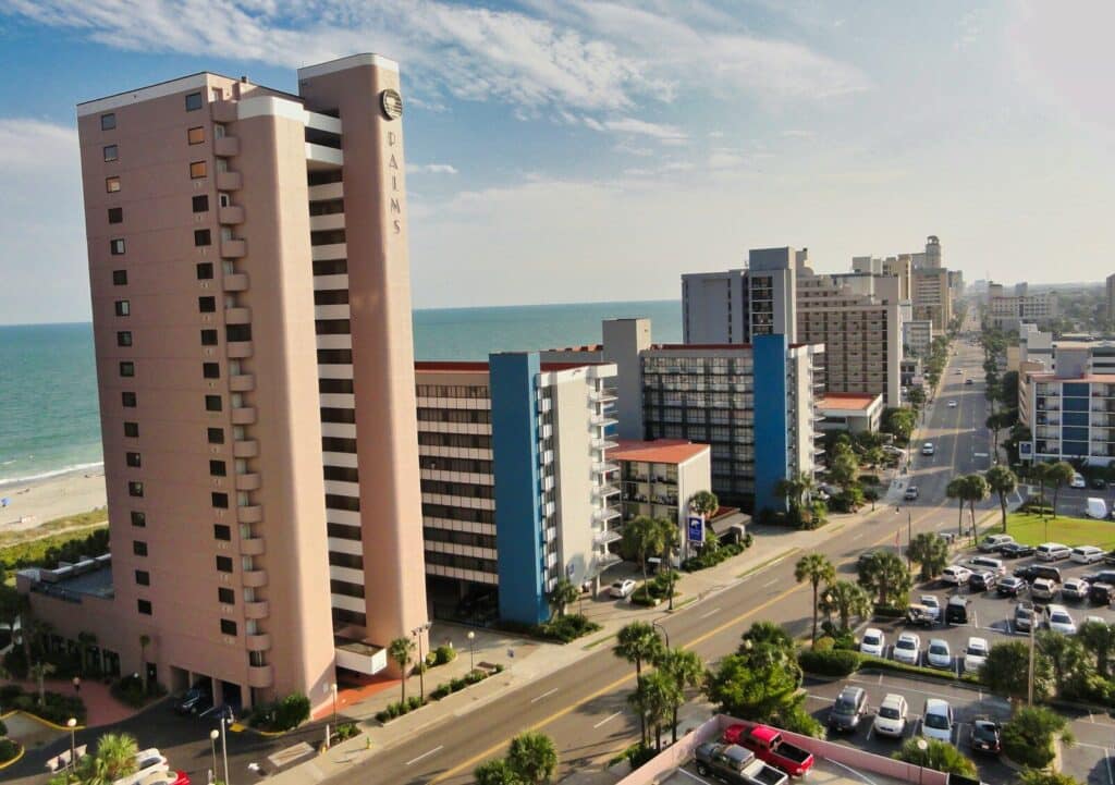 cars parked on parking lot near high rise buildings during daytime