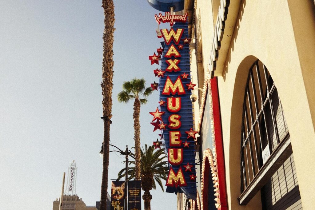 Hollywood Wax Museum sign with palm trees on sunny day, iconic Los Angeles location.