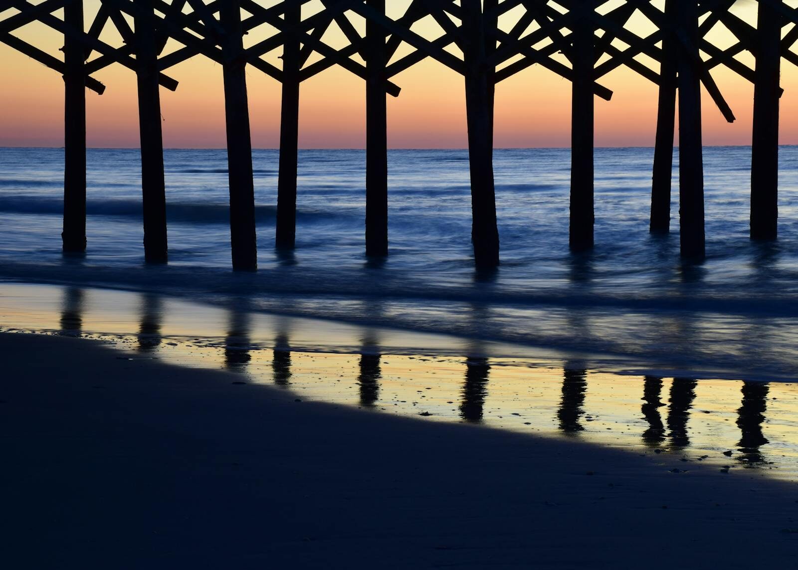 Serene sunset casting colorful reflections under Myrtle Beach pier.