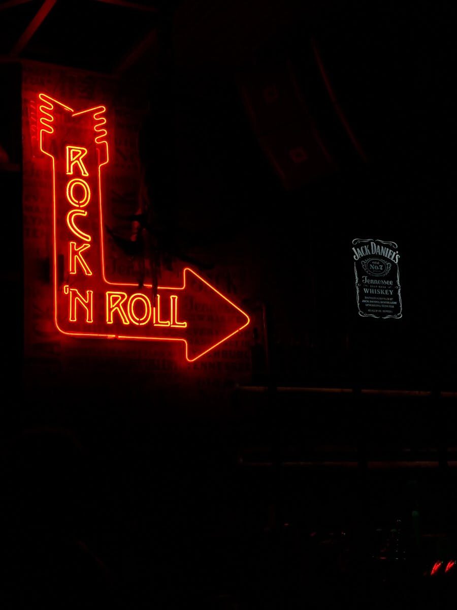 Red neon sign pointing with arrow, displaying 'Rock 'n Roll' text in a dimly lit atmosphere.