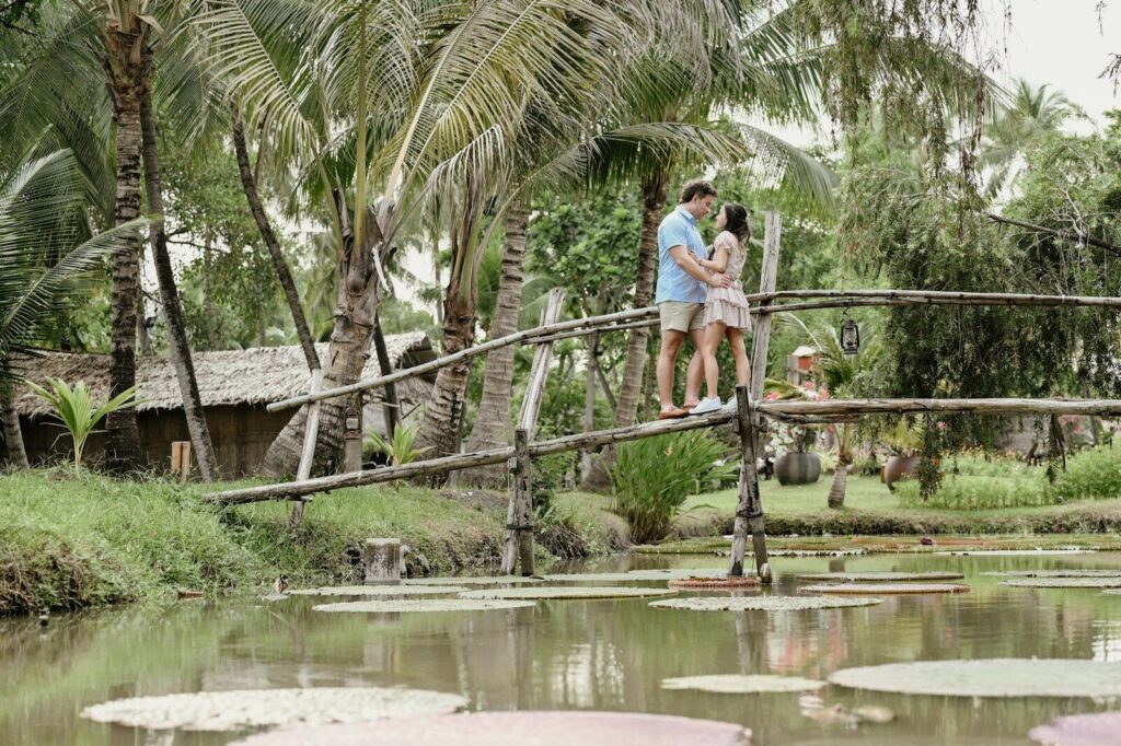Couple embracing on a rustic bridge surrounded by lush greenery