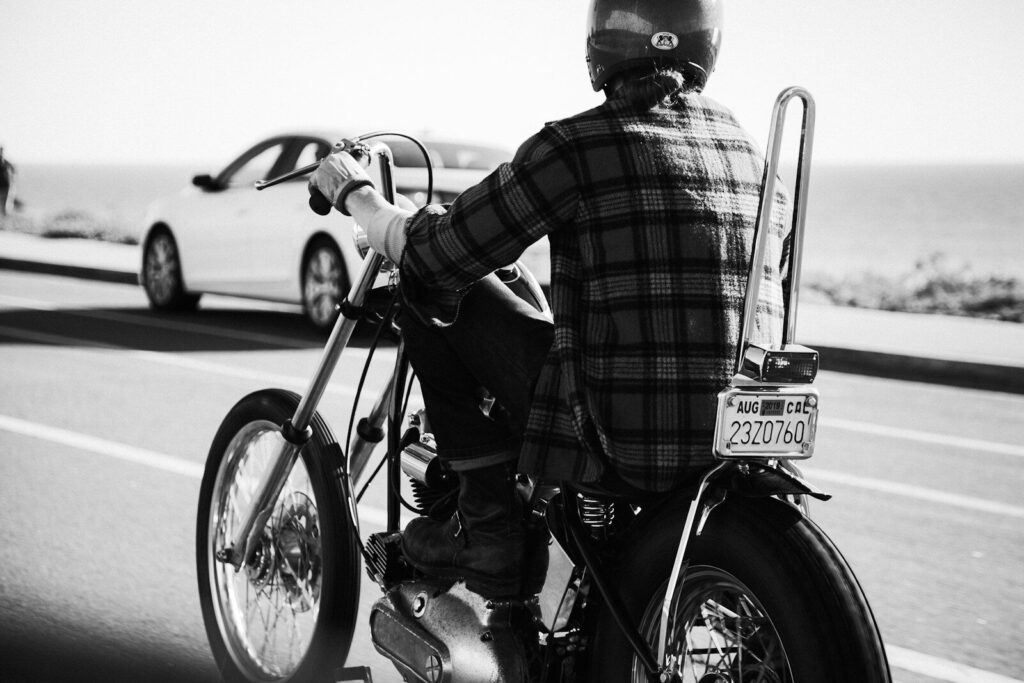 grayscale photo of person wearing plaid dress shirt riding chopper motorcycle