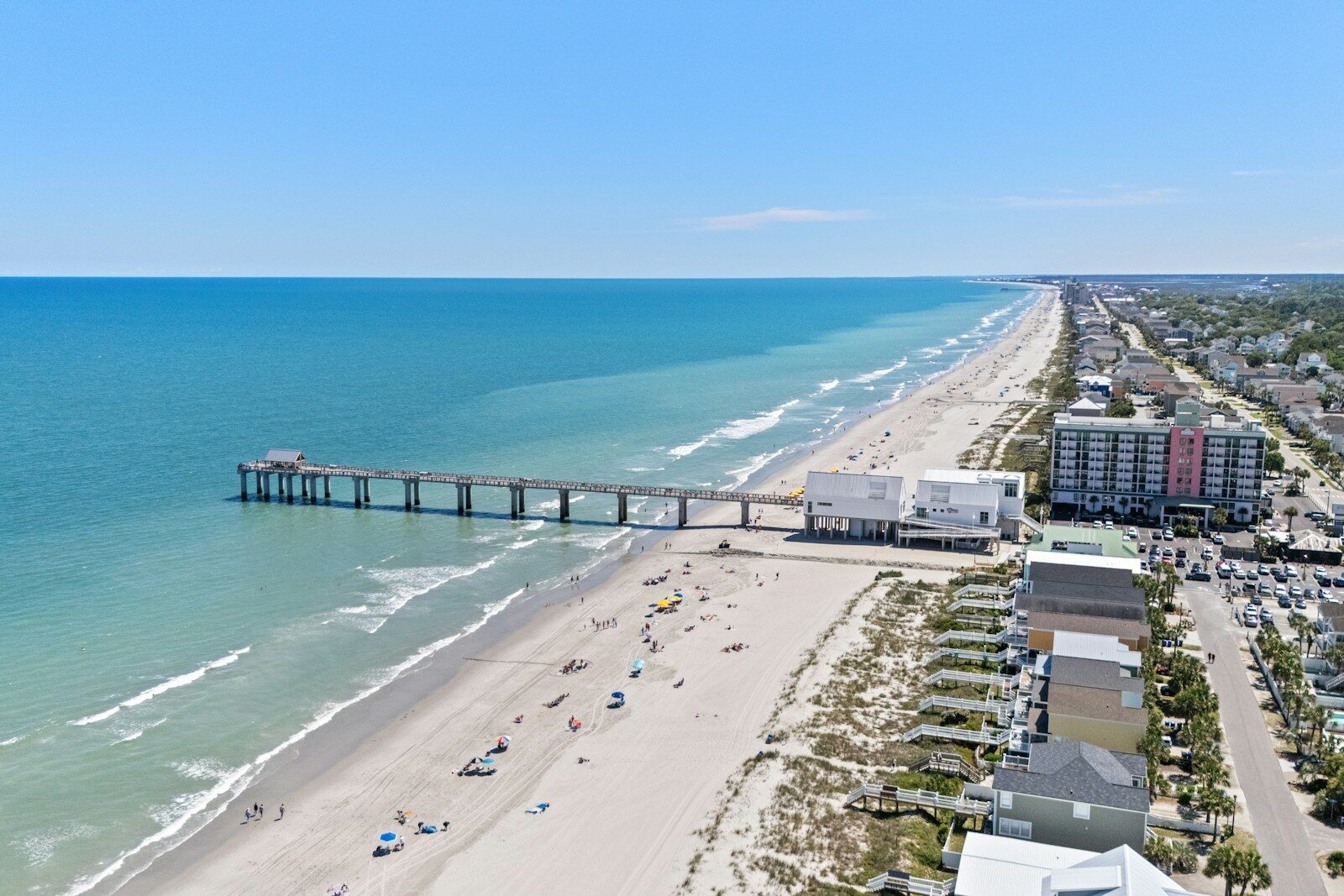 An aerial view of a beach with a pier in the distance