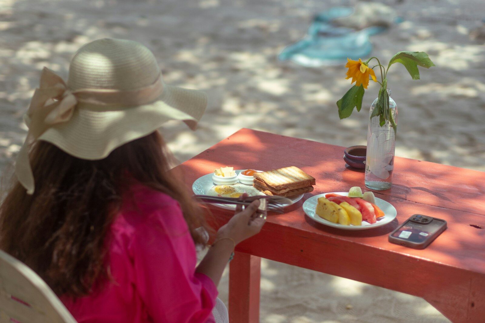 Woman eating breakfast on a beach table