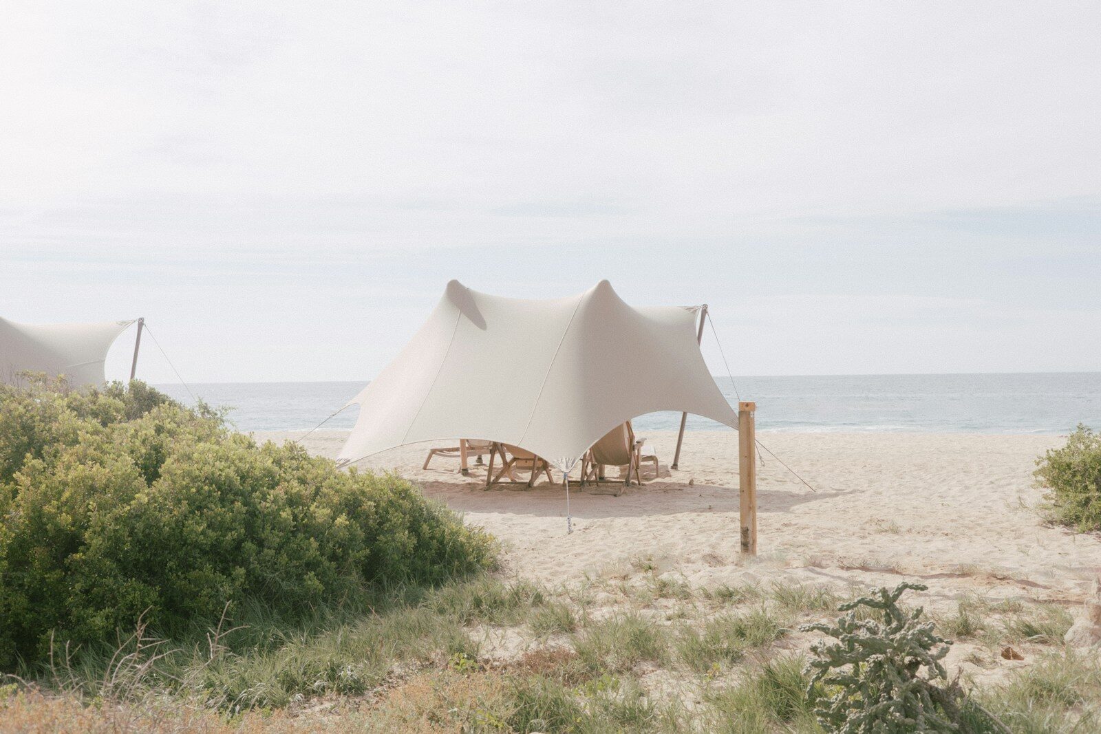 Two canvas tents set up on a sandy beach.