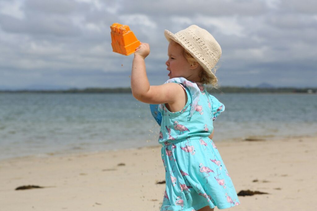a little girl holding a toy on a beach