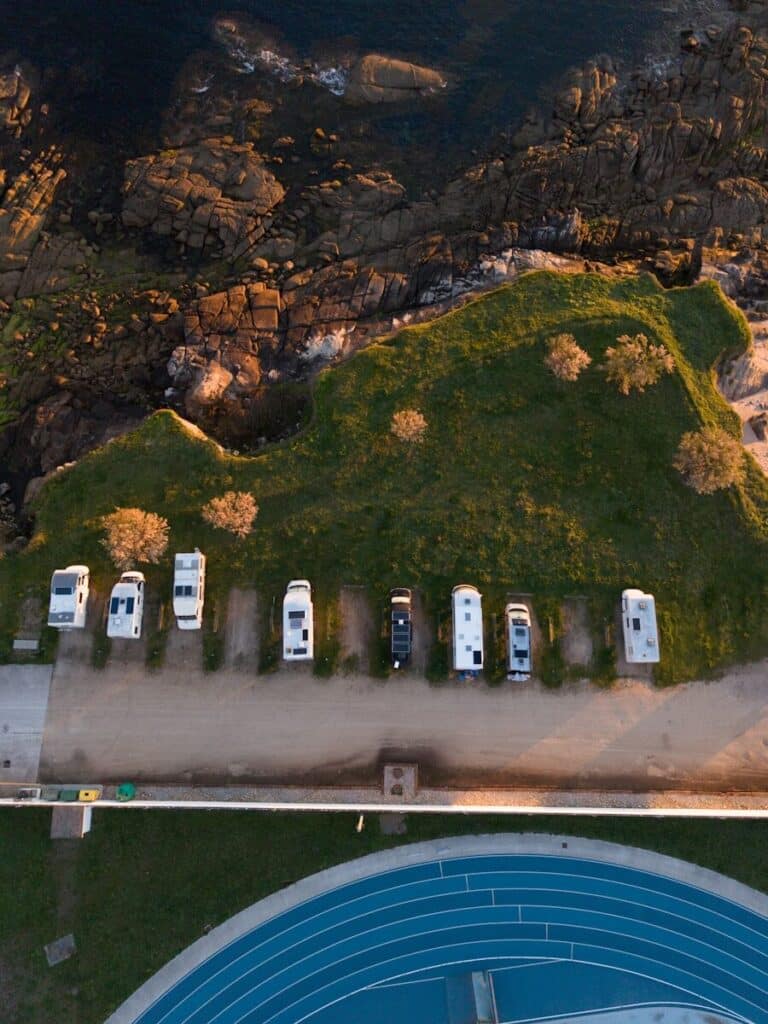 Rvs parked along a grassy coastline near a blue track.
