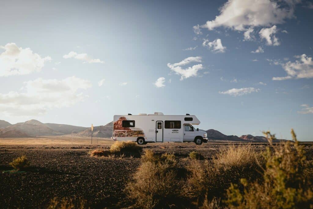 A white rv travels down a desert highway.